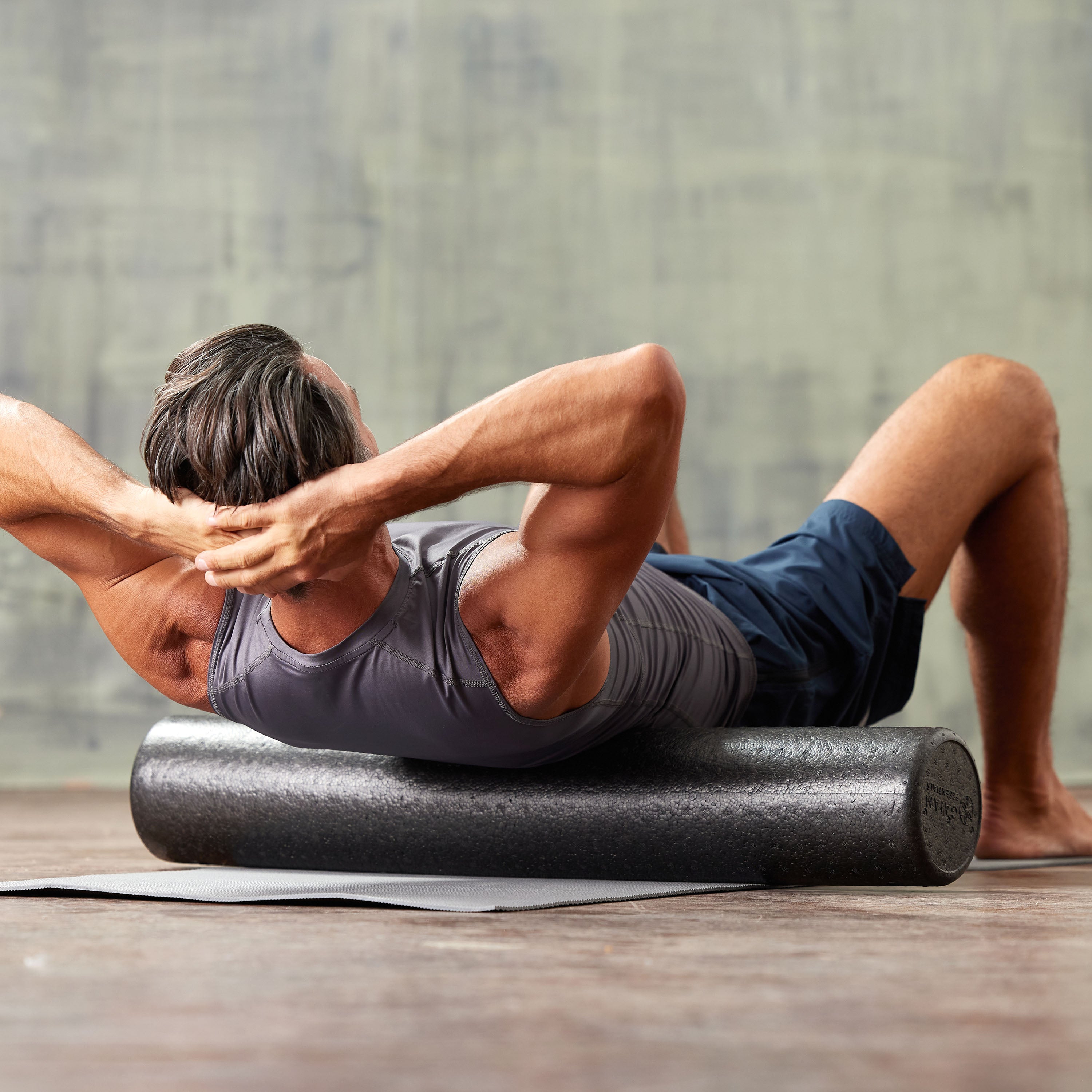 Person laying on the ground with the Essentials High-Density Foam Roller under the middle of the back